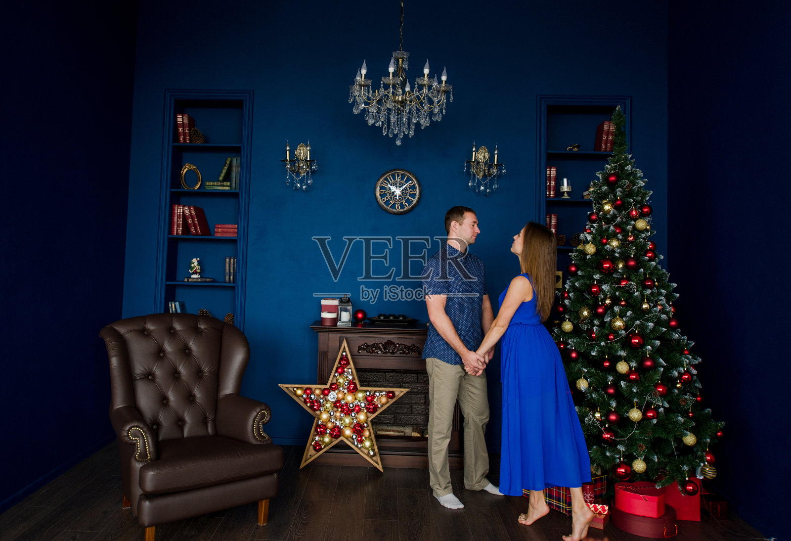 在蓝色的喜庆房间里，一对浪漫的情侣在圣诞树前跳舞照片摄影图片