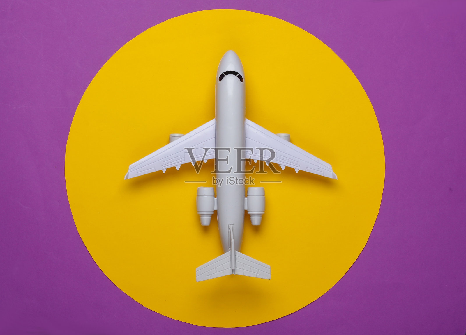 玩具模型的飞机在紫色的背景与黄色的圆圈。旅游的概念，航空旅行，极简主义。俯视图照片摄影图片