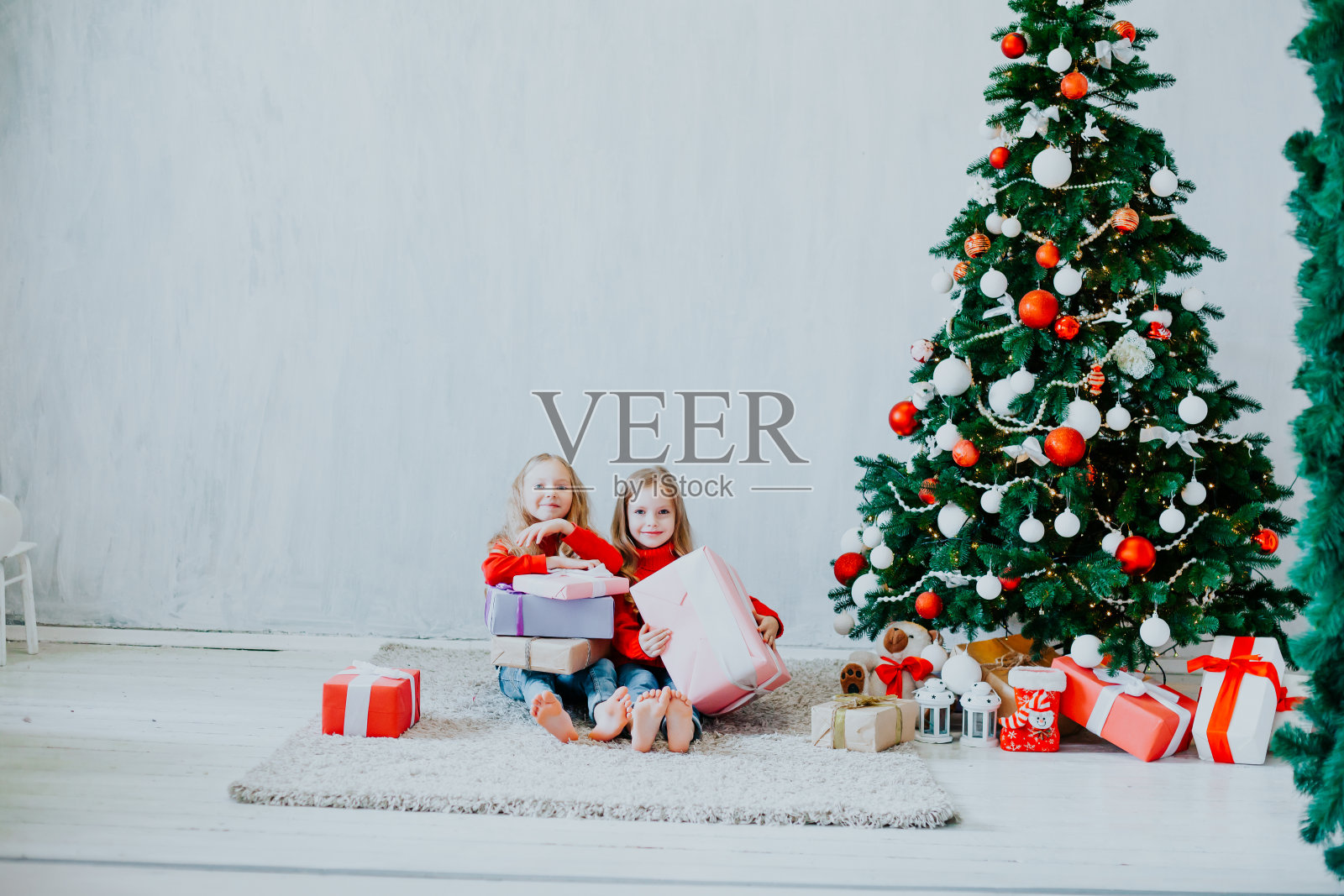 圣诞节两个女孩带着礼物新年圣诞树上放着灰色背景的礼物照片摄影图片