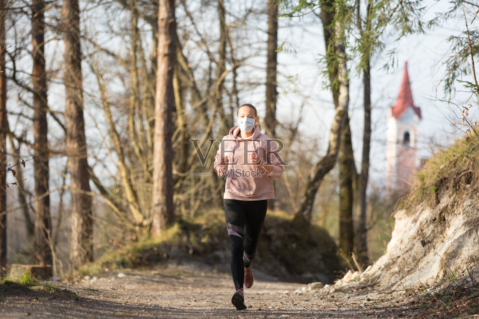 冠状病毒(Covid-19)正在全球蔓延。肖像的白人运动妇女戴着医疗保护口罩，而在自然中跑步。照片摄影图片