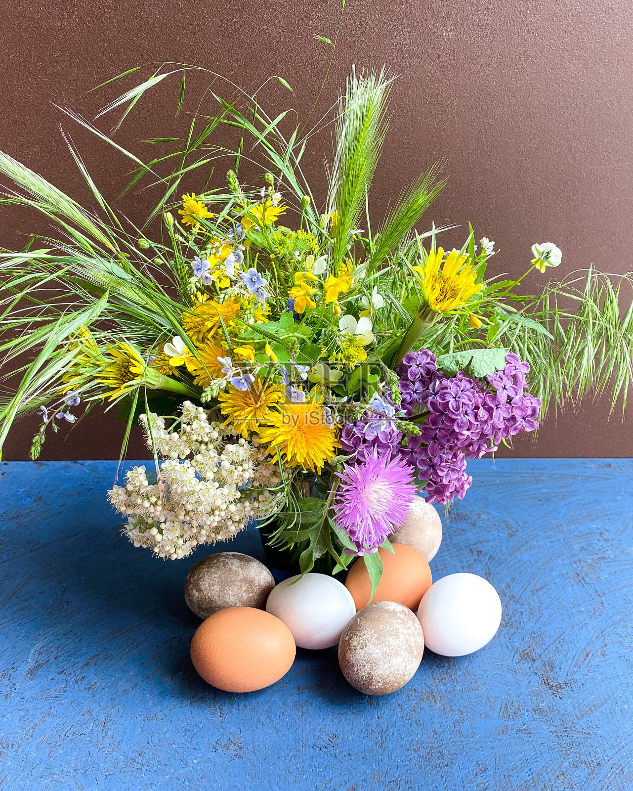 五彩缤纷的复活节彩蛋和鲜艳的野花在装饰花瓶，在一个抽象的表面背景。照片摄影图片