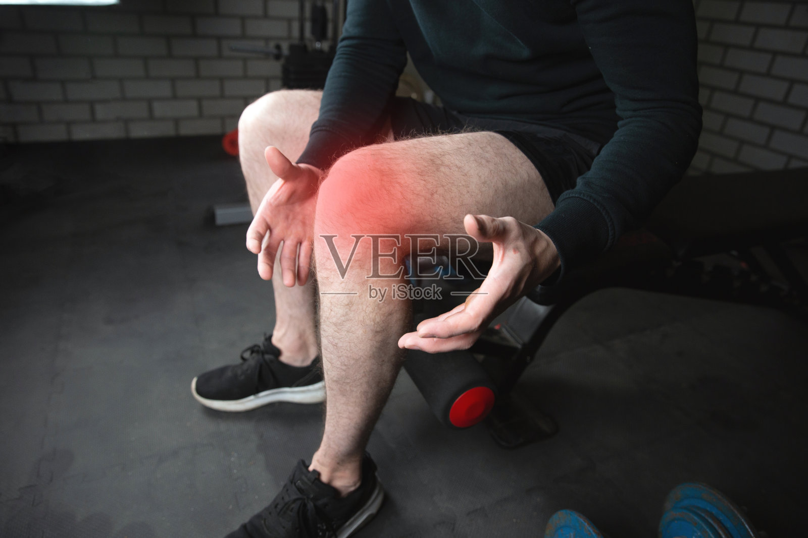 一个肌肉健康的人的肖像达到他的膝盖疼痛，男人从运动损伤在健身房与红色包围的腿部特写照片摄影图片