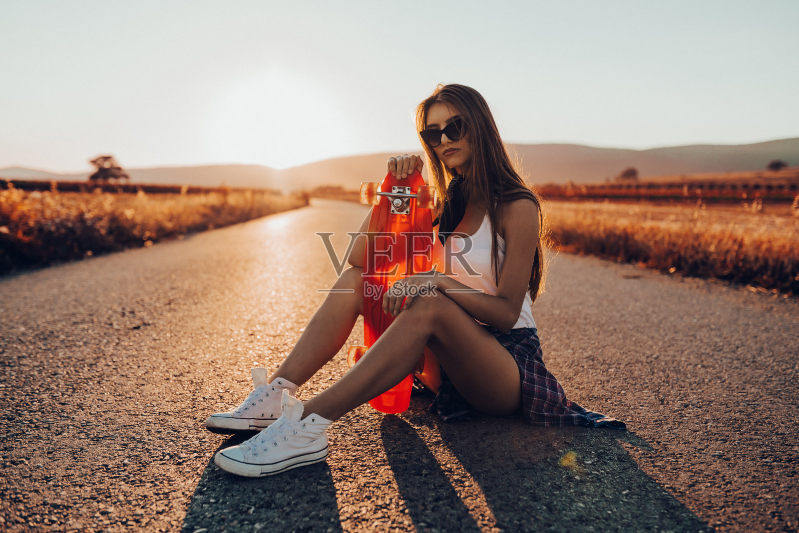 一个玩滑板的少女在一个阳光明媚的夏日照片摄影图片