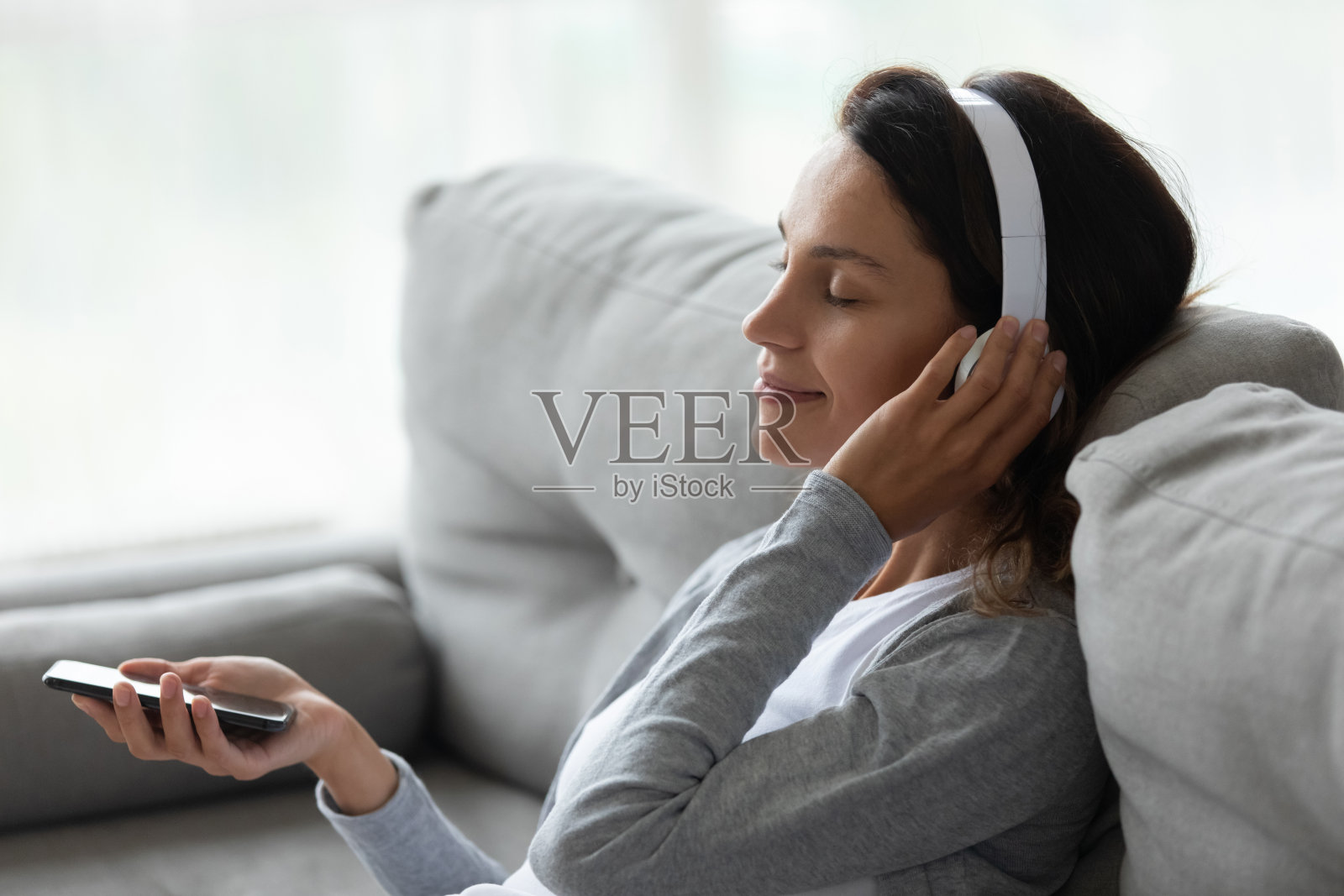 冷静的女人戴着耳机享受喜欢的音乐，拿着手机照片摄影图片