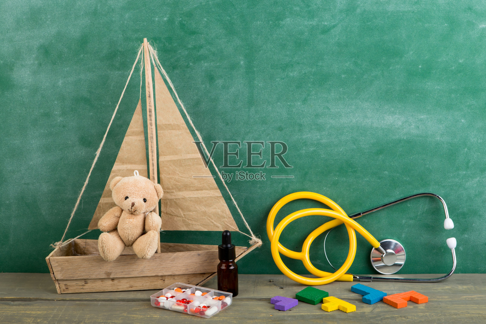 足科医生工作场所-玩具熊，听诊器和木桌上的药品-儿童保健理念照片摄影图片