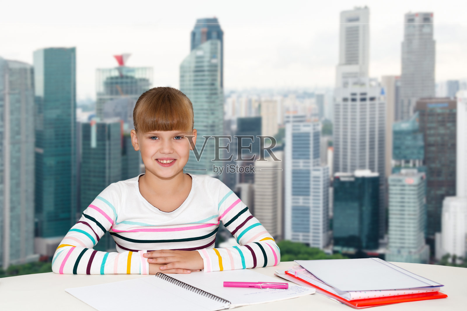 教育，人，孩子和学校的概念-小学生女孩坐在桌子与笔记本城市的背景照片摄影图片