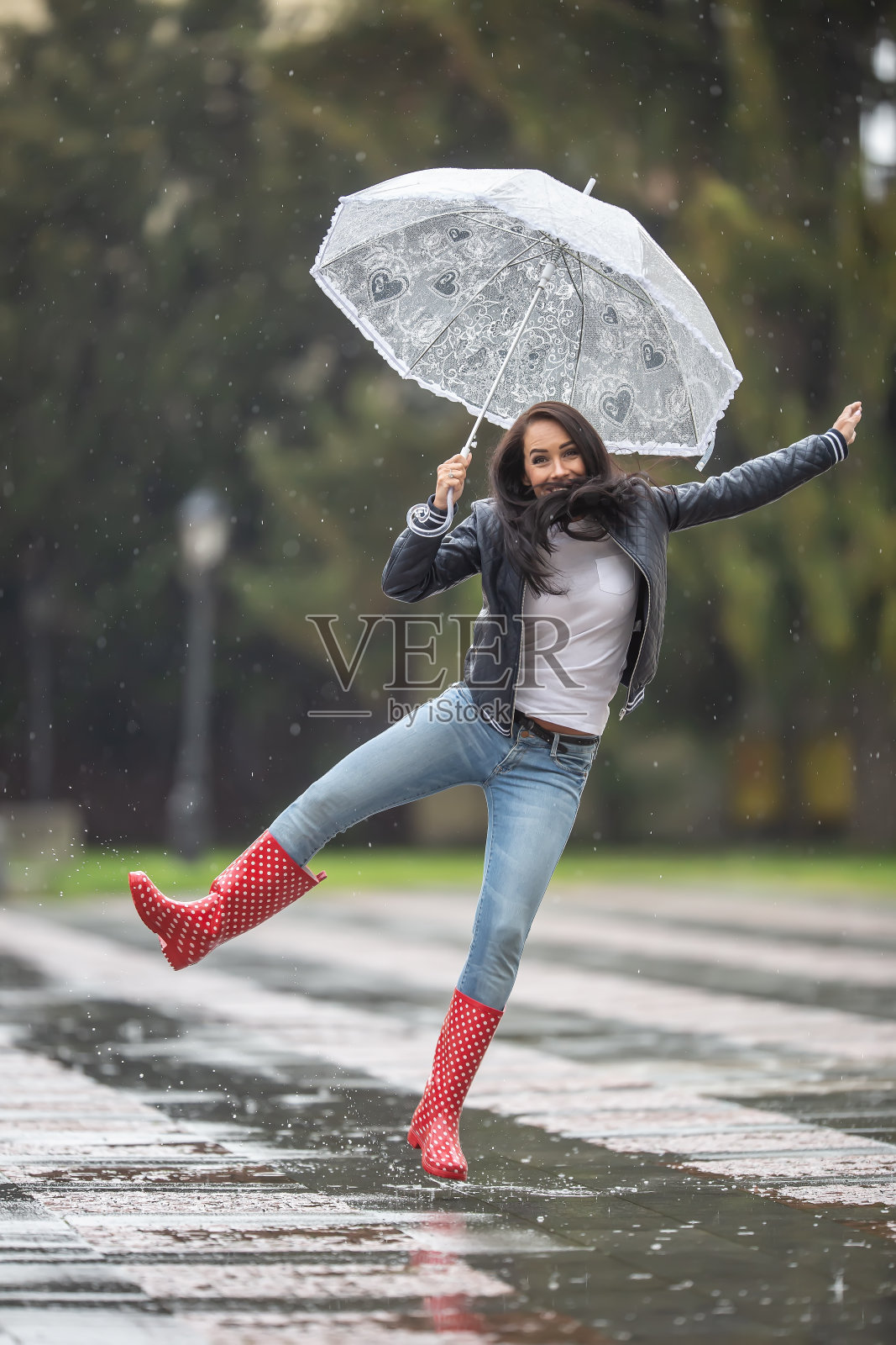 女人从喜悦的雨天与伞和红色圆点雨靴。照片摄影图片