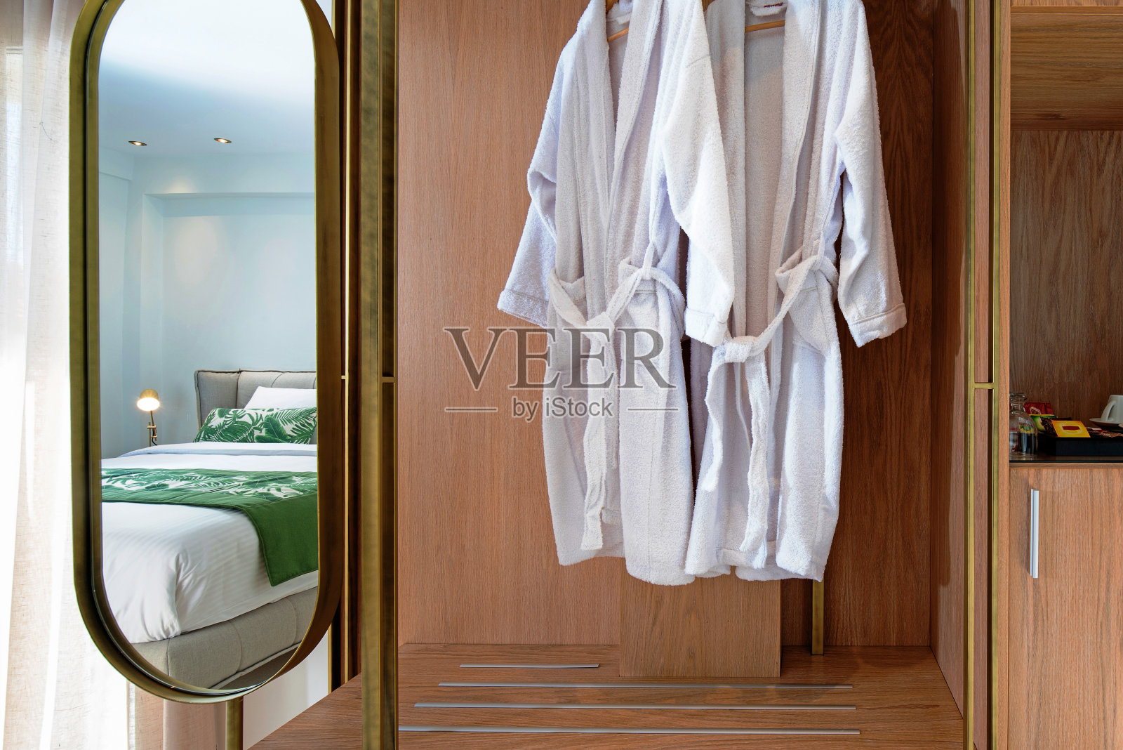 木质衣柜前视图与镜子和挂白色浴衣在现代酒店房间内部照片摄影图片