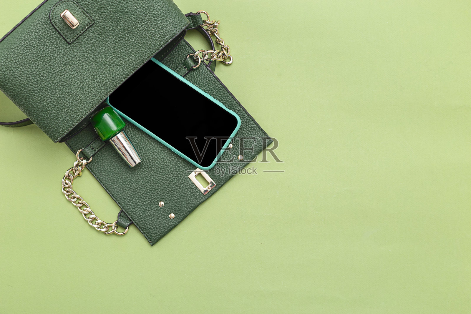 手提包，手机，指甲油，绿色背景。单色。最小的。本空间照片摄影图片