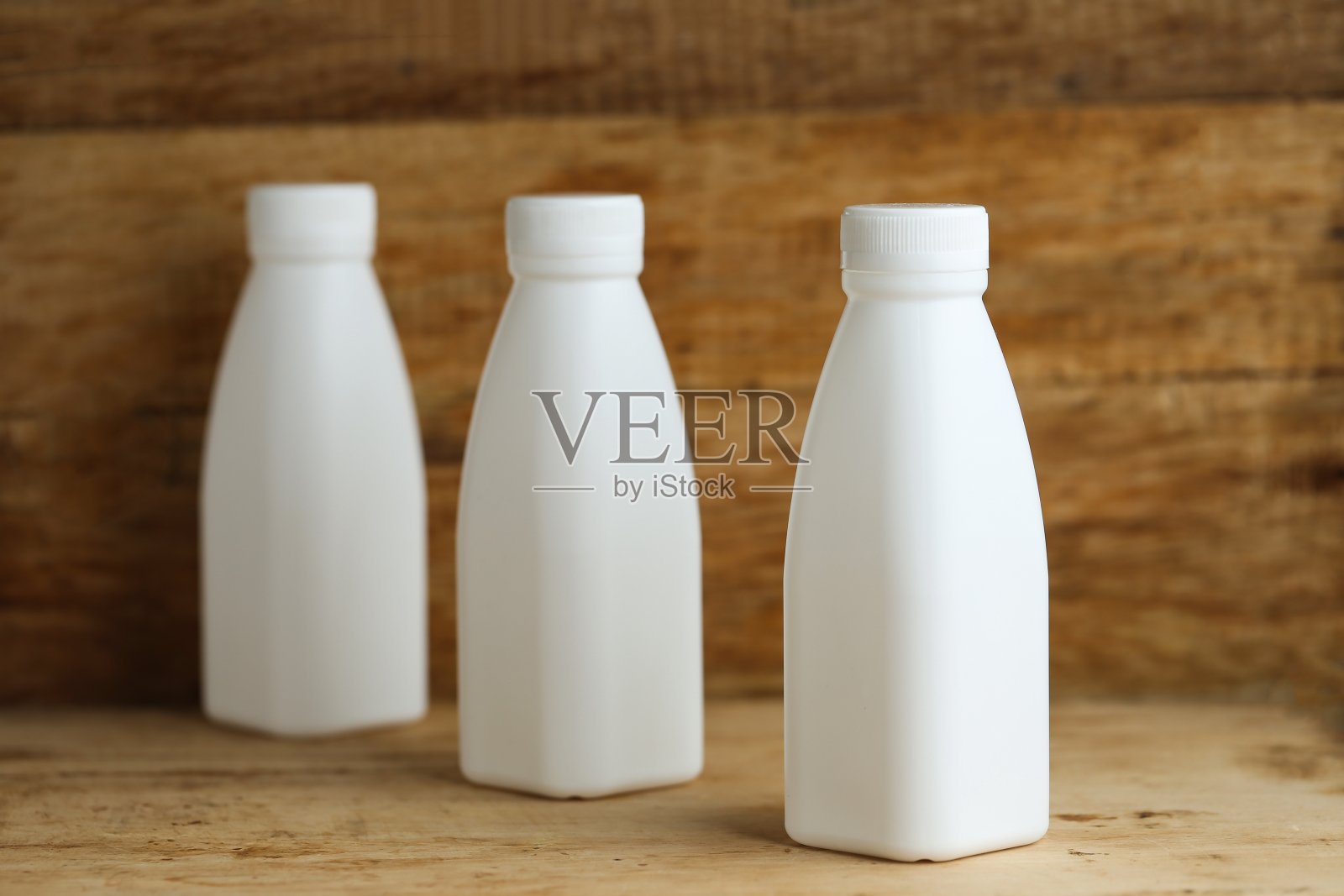 白色塑料牛奶瓶在复古的木制桌子背景照片摄影图片