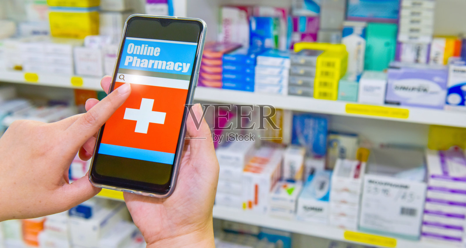 药剂师用移动智能手机进行搜索，显示在药店货架的后台。照片摄影图片