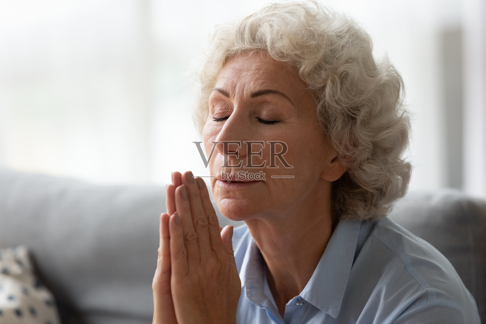 老妇人闭着眼睛祈祷，双手合十照片摄影图片