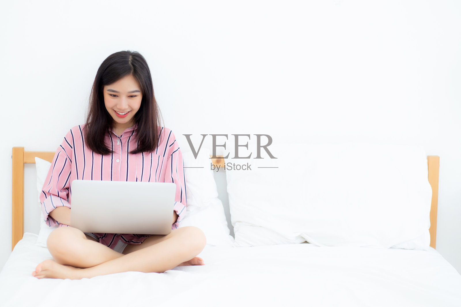美丽肖像自由亚洲年轻女子坐着放松和休闲工作笔记本电脑上网上网在床上的卧室，开朗的亚洲女孩与姿态高兴和成功，生活理念。照片摄影图片