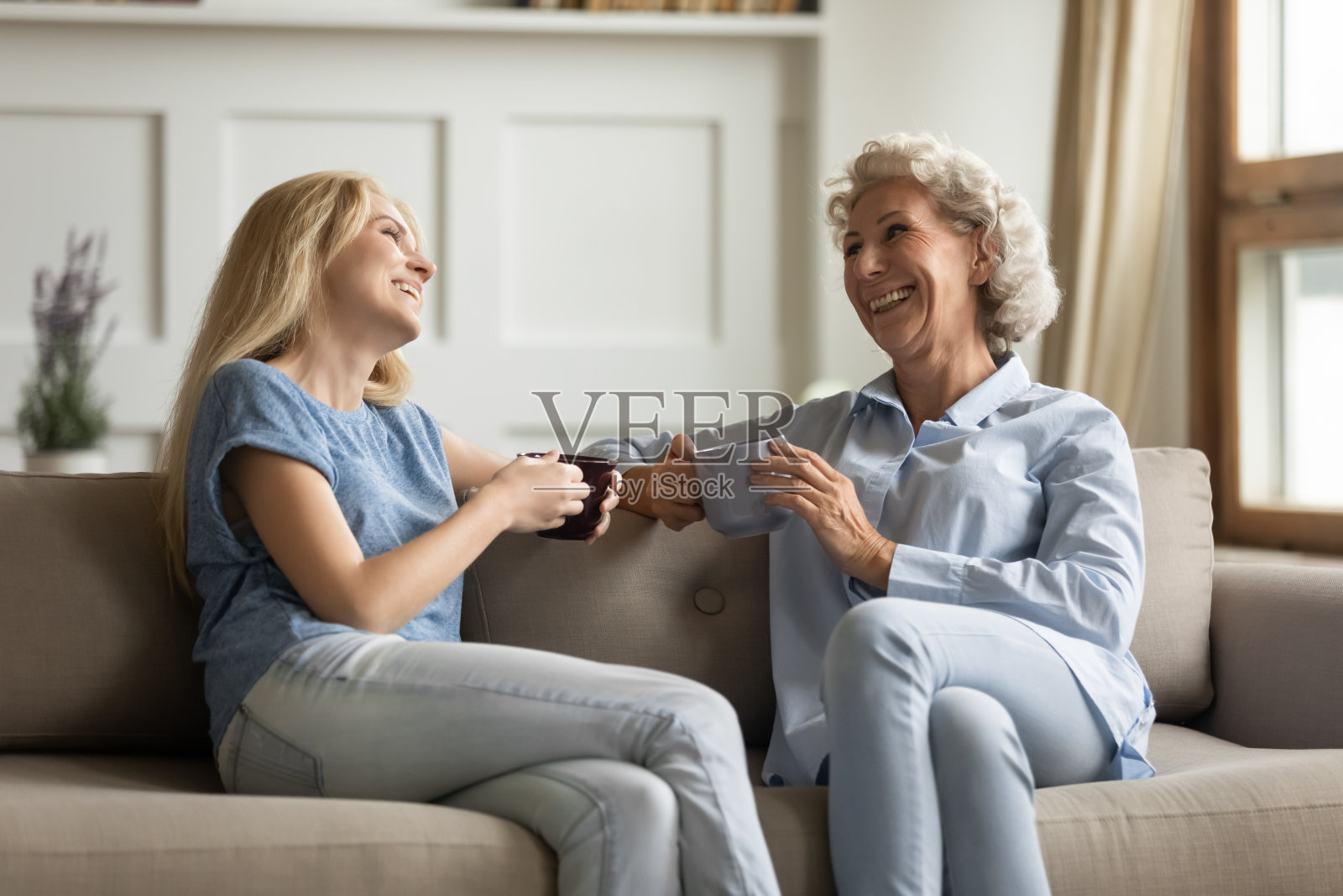 千禧女儿与年长的母亲在愉快的交谈中喝茶照片摄影图片