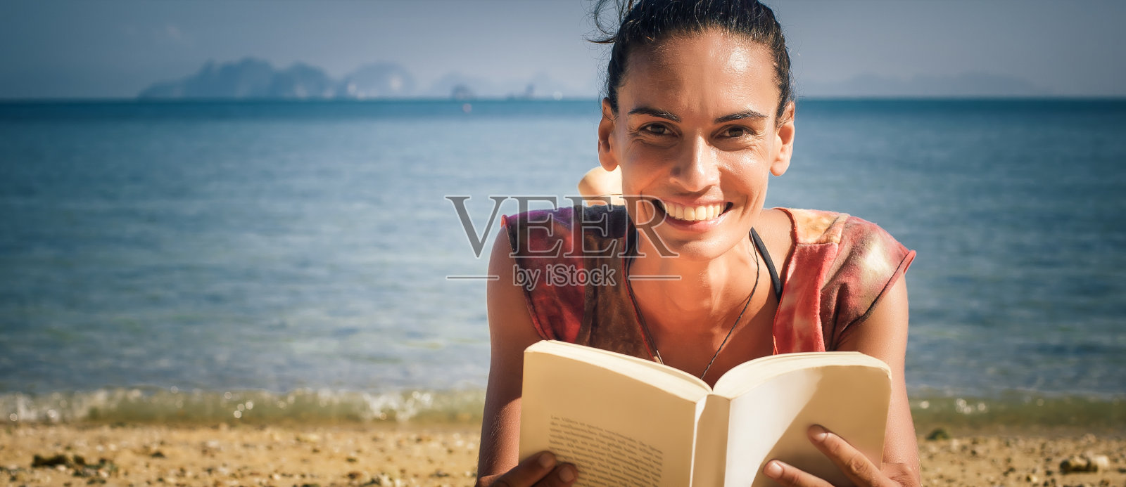 女人一边看书一边享受海滩上的阳光照片摄影图片
