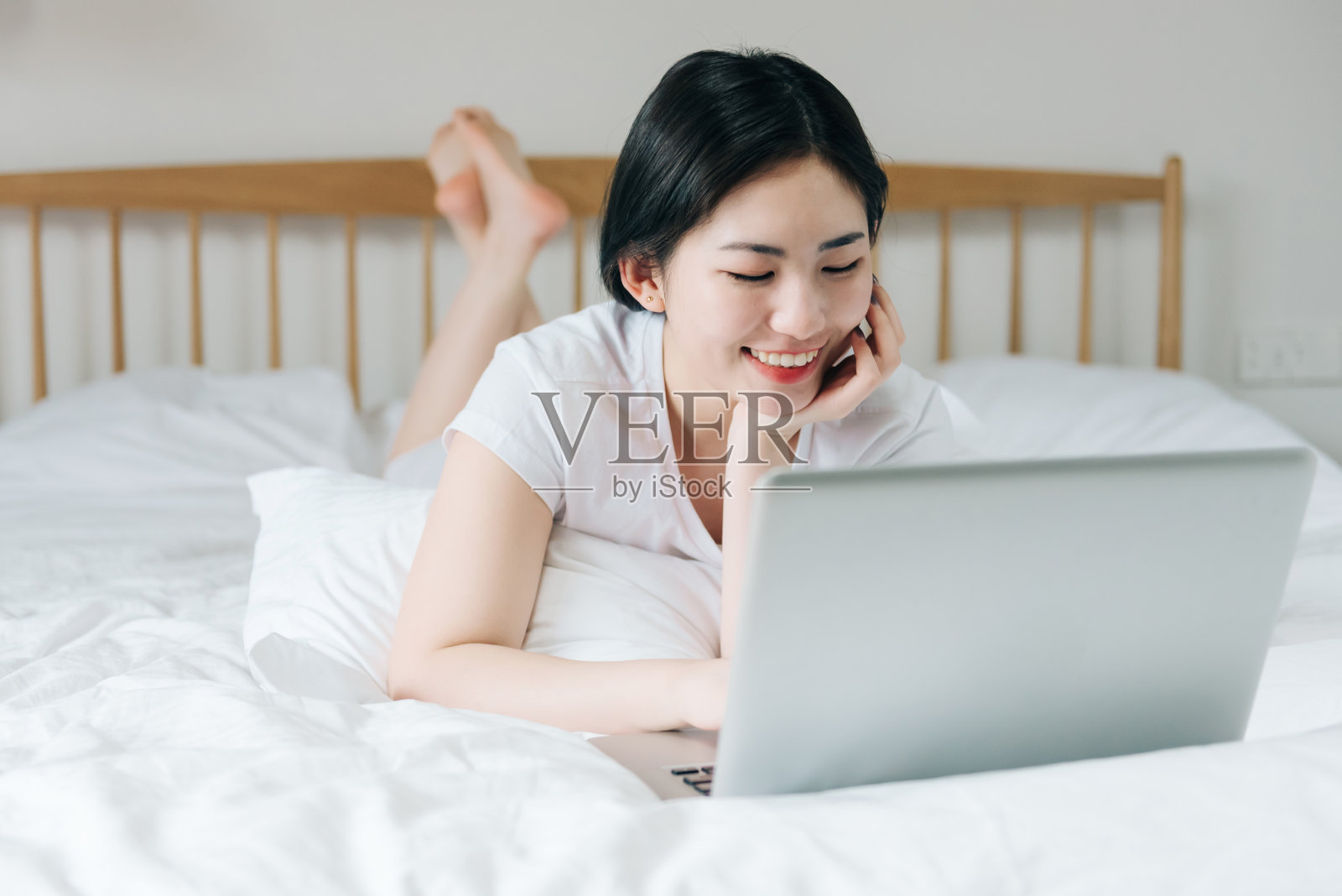 年轻的亚洲女孩在床上使用笔记本电脑照片摄影图片