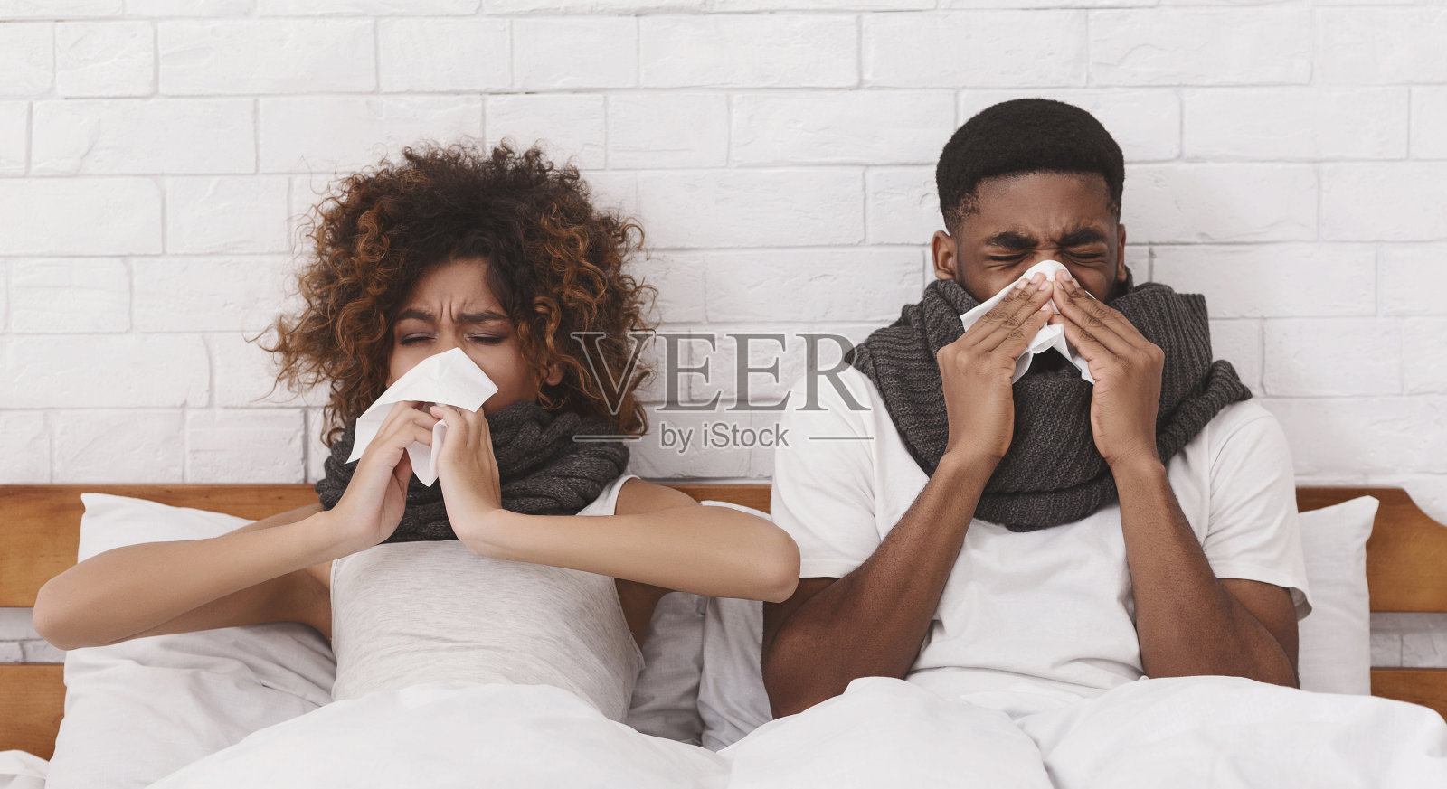 生病的非裔美国夫妇在床上擤鼻涕照片摄影图片