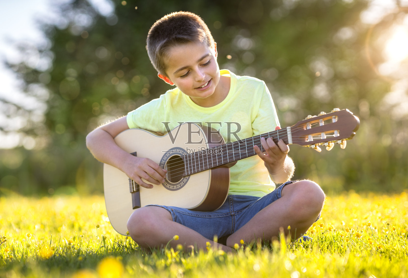 日落时分，男孩在田野里弹吉他照片摄影图片