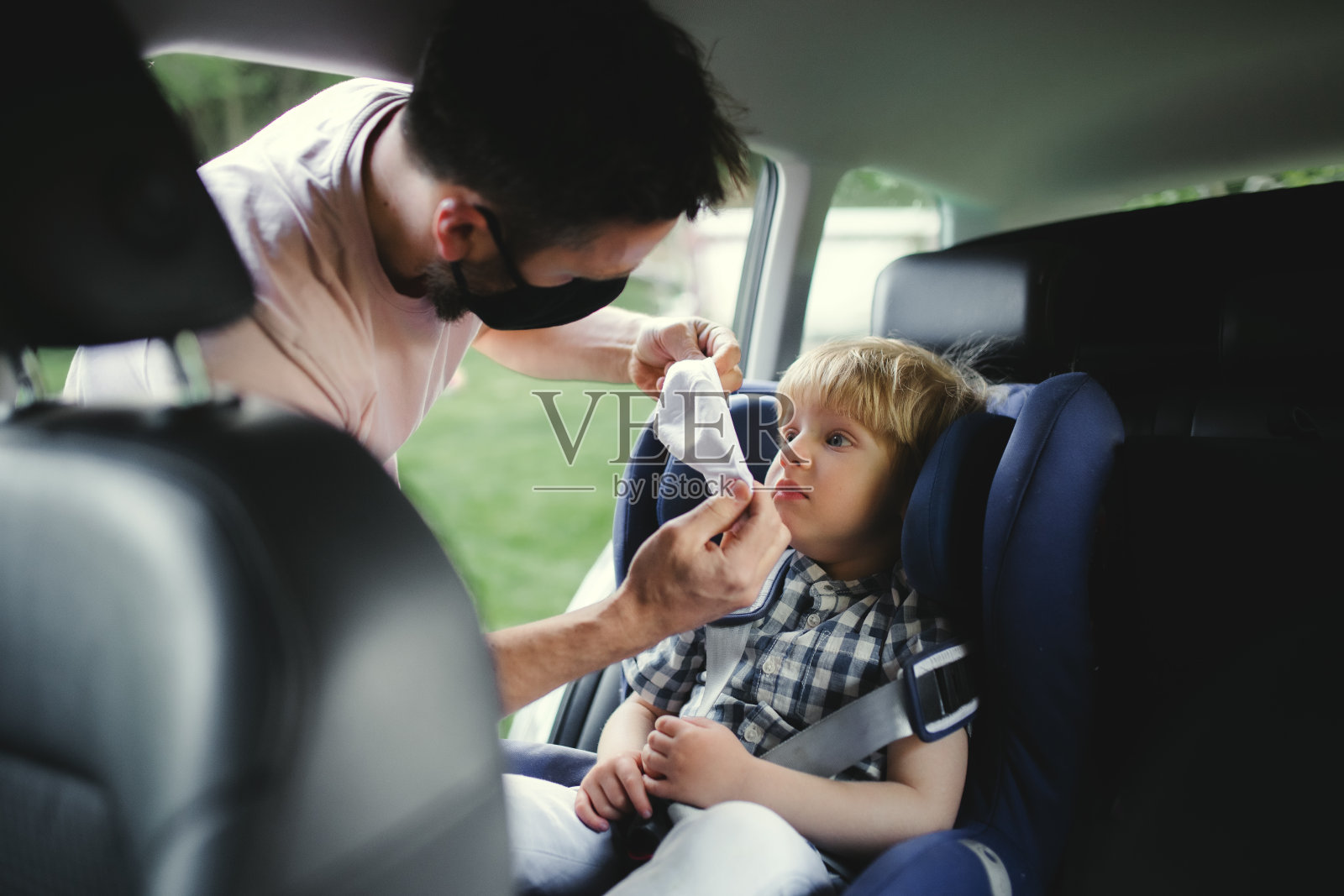 父亲带着小儿子开车去旅行，戴着口罩。照片摄影图片