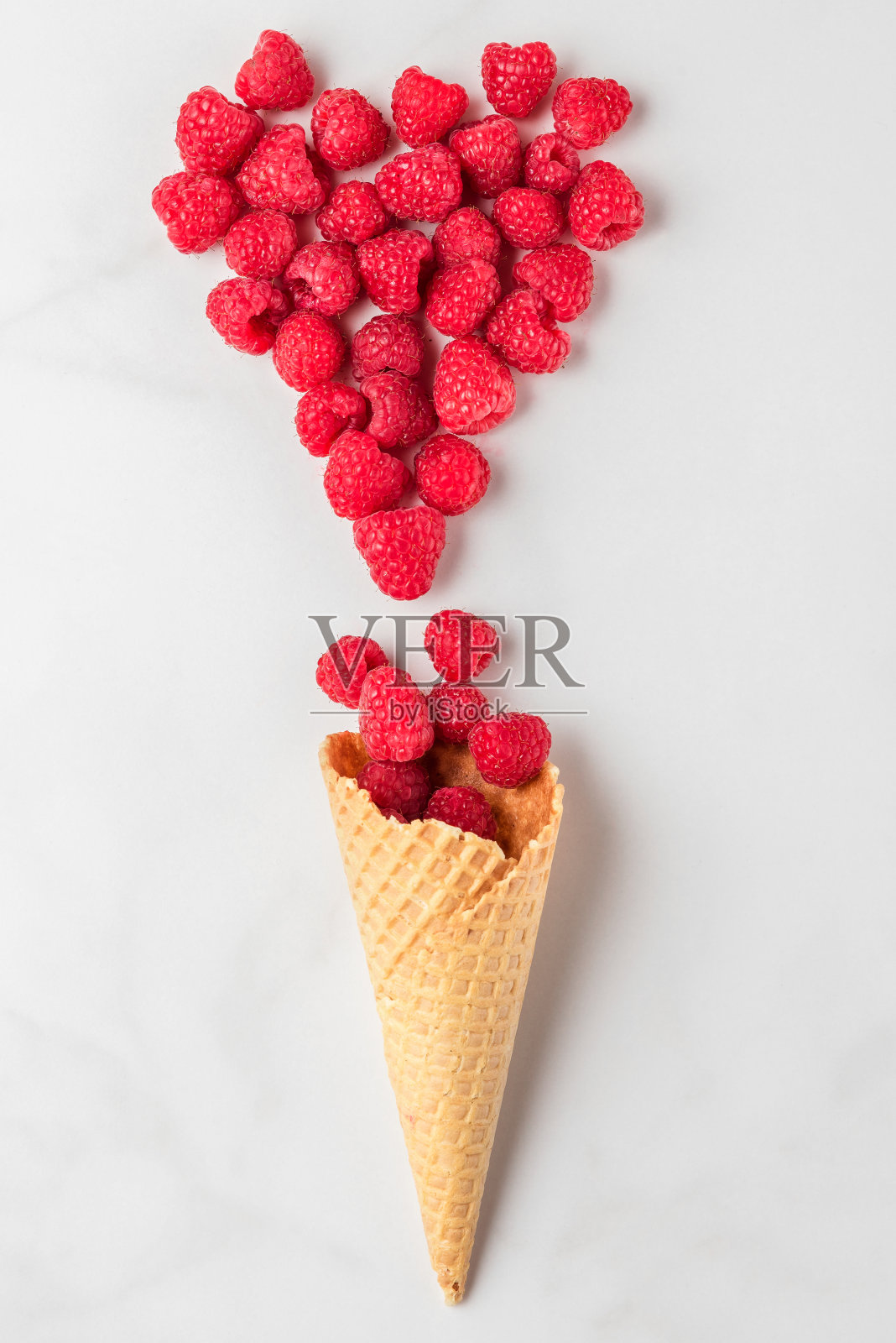 新鲜的夏季覆盆子在华夫蛋筒冰淇淋，心形的浆果在白色大理石的背景照片摄影图片