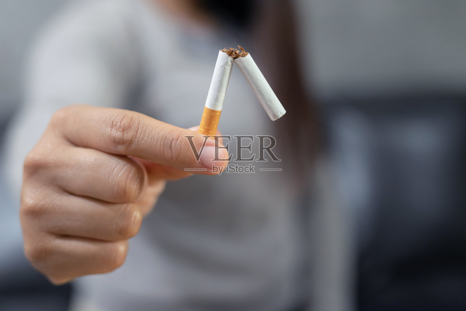 戒烟。女孩手中握着香烟的概念快乐的女性戒烟戒烟的坏习惯不吸烟的保健概念照片摄影图片