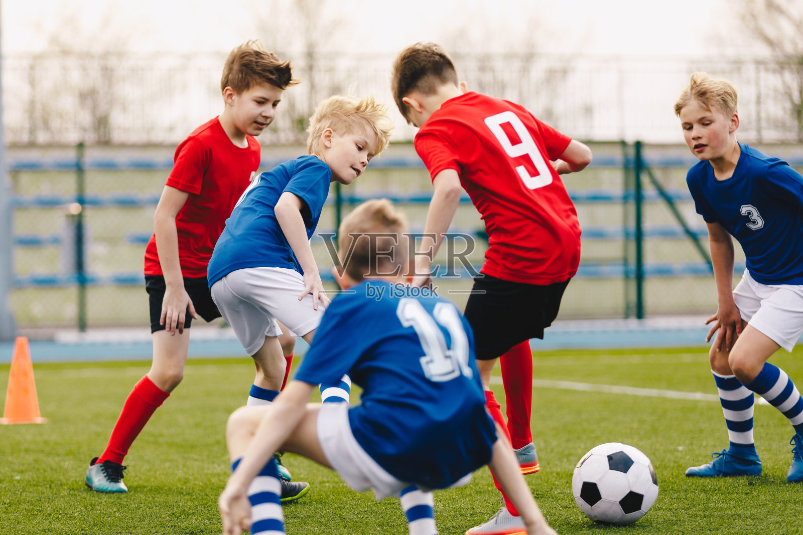 学校男生在踢足球。年轻球员在草地上踢足球。快乐的孩子们在操场上比赛照片摄影图片