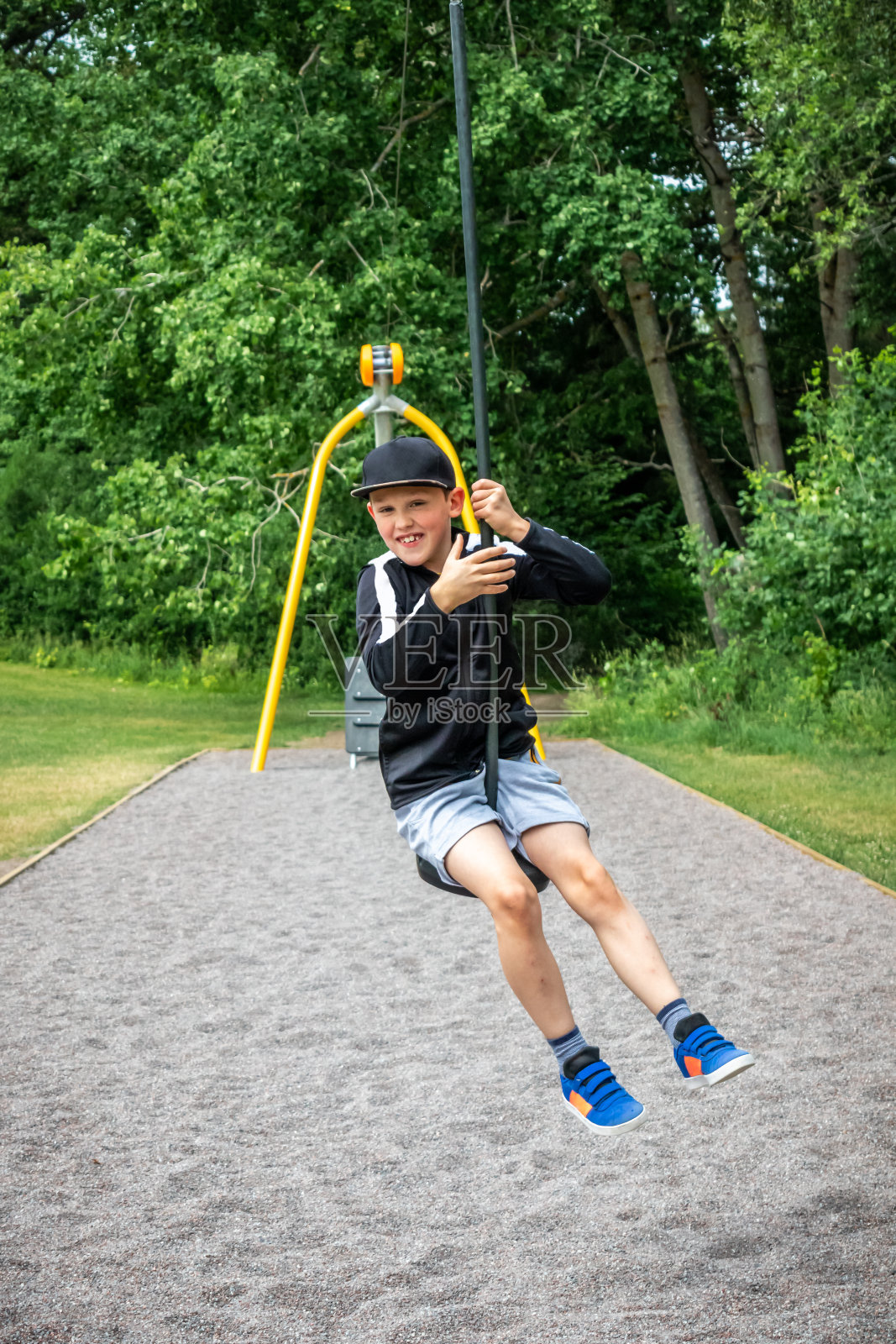 运动的孩子微笑着在一个公共公园的操场上滑索。照片摄影图片