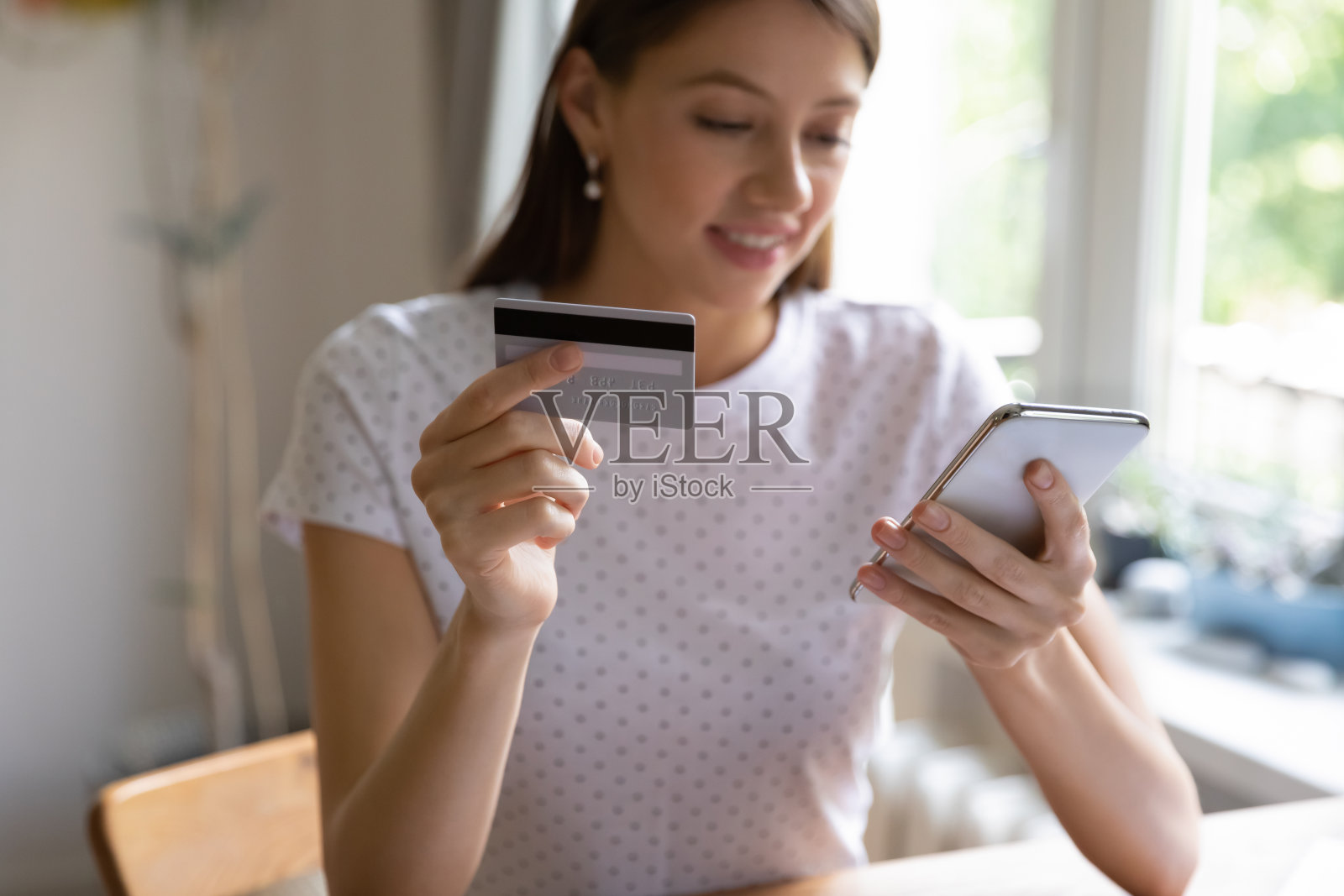 年轻女子用信用卡在手机上付款照片摄影图片