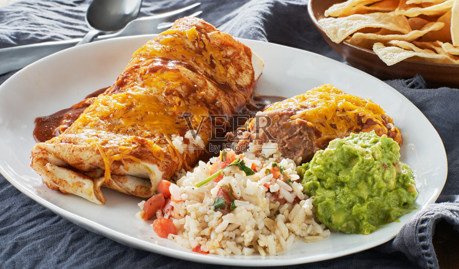 墨西哥湿玉米卷拼盘，配红玉米卷酱汁，炸豆，米饭和鳄梨酱照片摄影图片