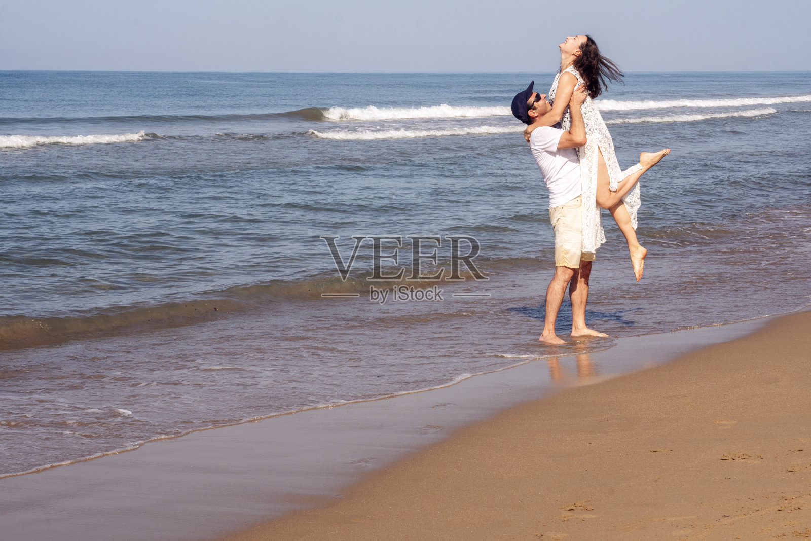 金色沙滩上一对幸福的情侣。男人抱着女人，充满爱意。照片摄影图片