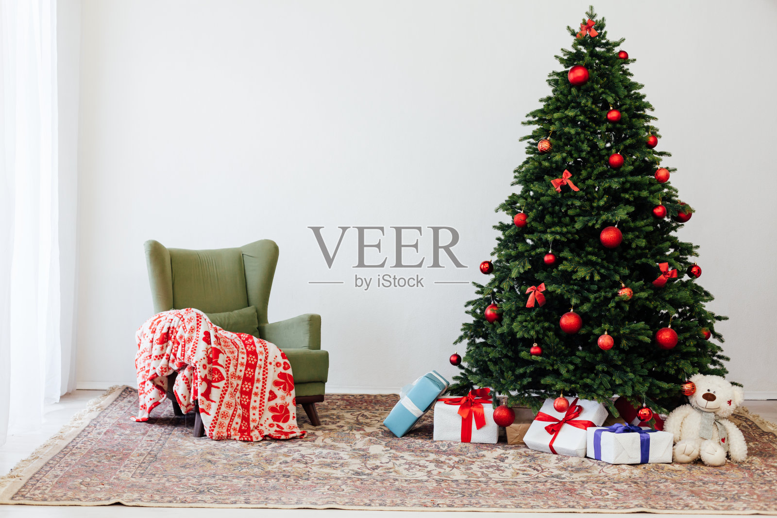 白色房间的内部是一棵绿色的圣诞树，上面挂着红色的礼物，作为新年的装饰照片摄影图片