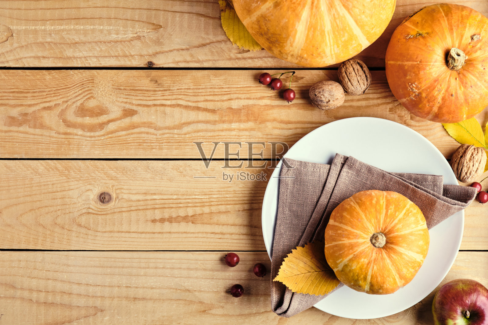 感恩节庆祝概念。秋天的构图与盘子，成熟的橙色南瓜，落叶，水果，坚果在质朴的木桌上。平铺，俯视图，拷贝空间。照片摄影图片