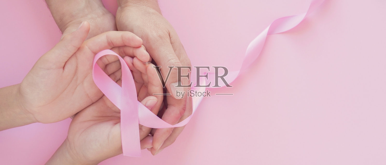 成人和儿童手牵粉红丝带，乳腺癌意识，十月粉红，世界癌症日的概念照片摄影图片
