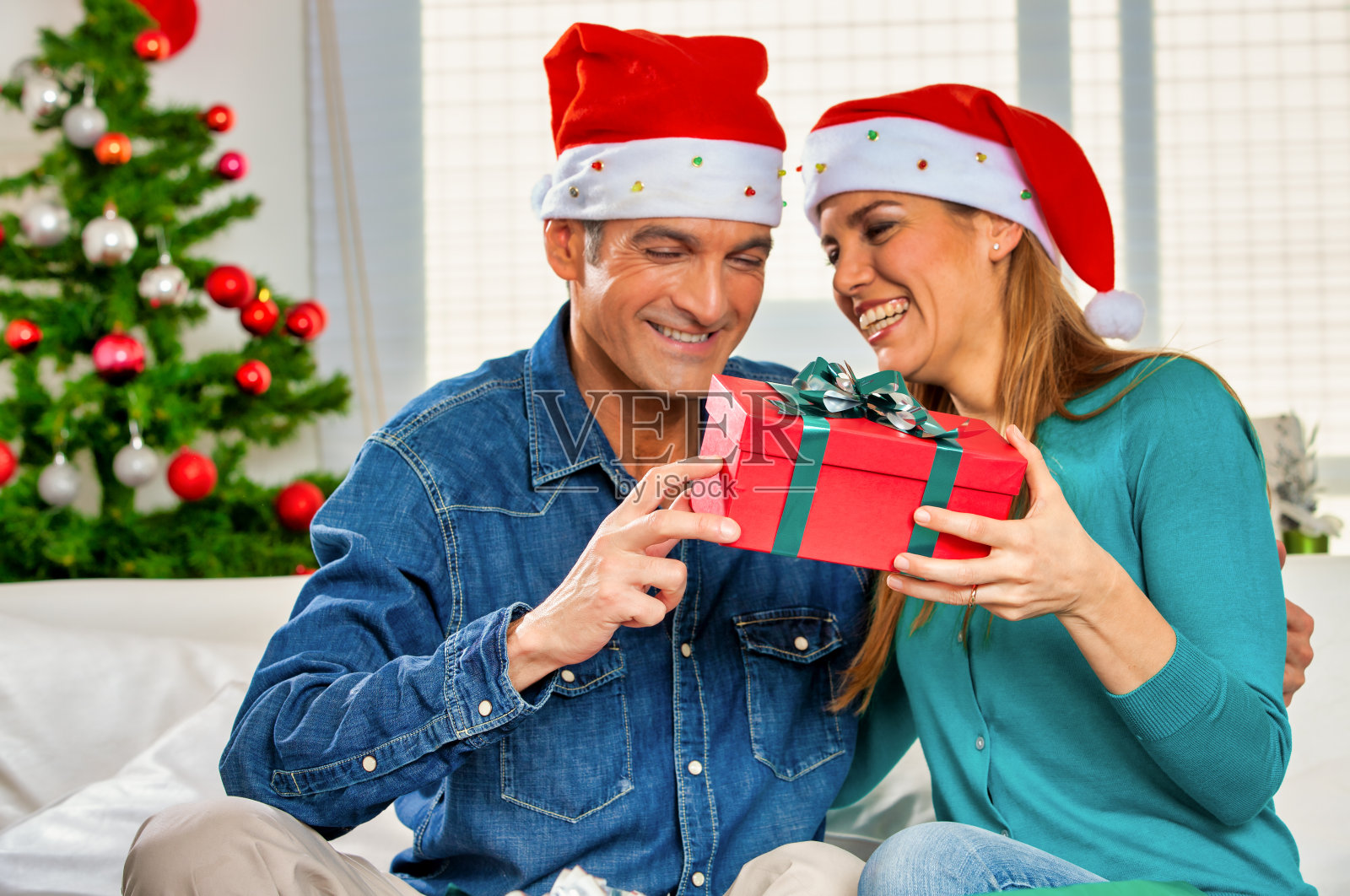 12月假期。圣诞,甜蜜的时刻。微笑的妻子收到圣诞前夜从丈夫的圣诞礼物肖像照片摄影图片
