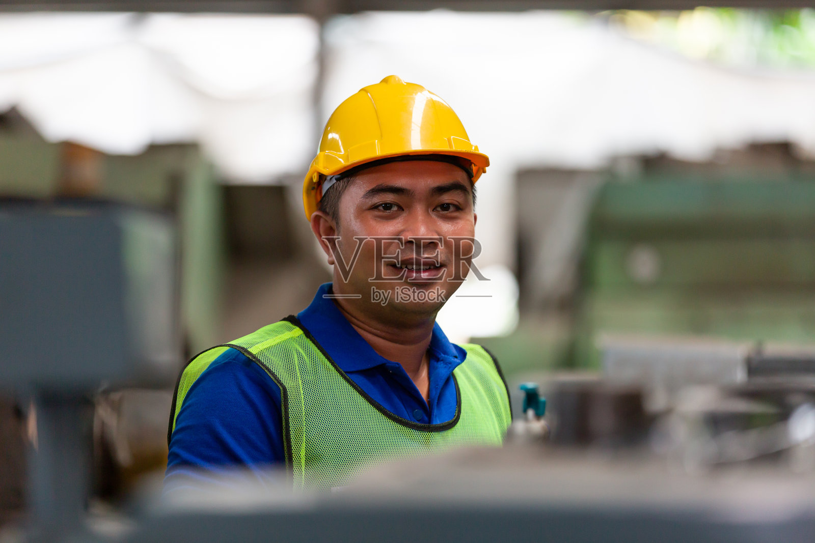 亚洲男性产业工人在工业工厂里穿着安全制服和黄色头盔看着摄像机照片摄影图片