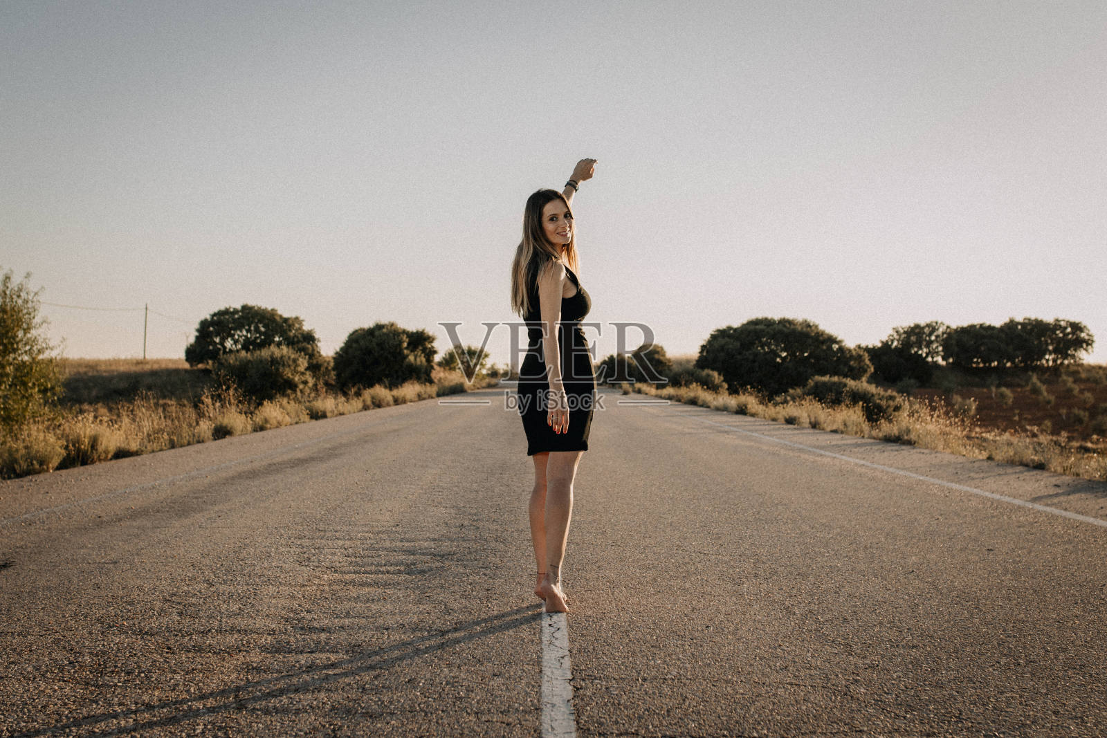 一个穿黑衣服的女人走在空旷的路上照片摄影图片