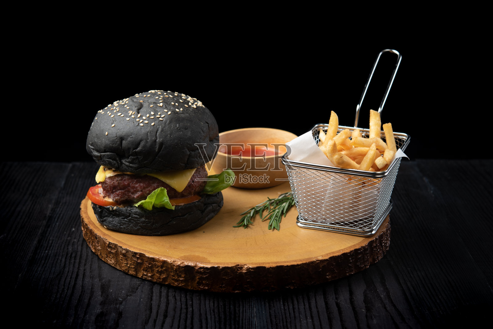黑汉堡和炸薯条放在木砧板上照片摄影图片