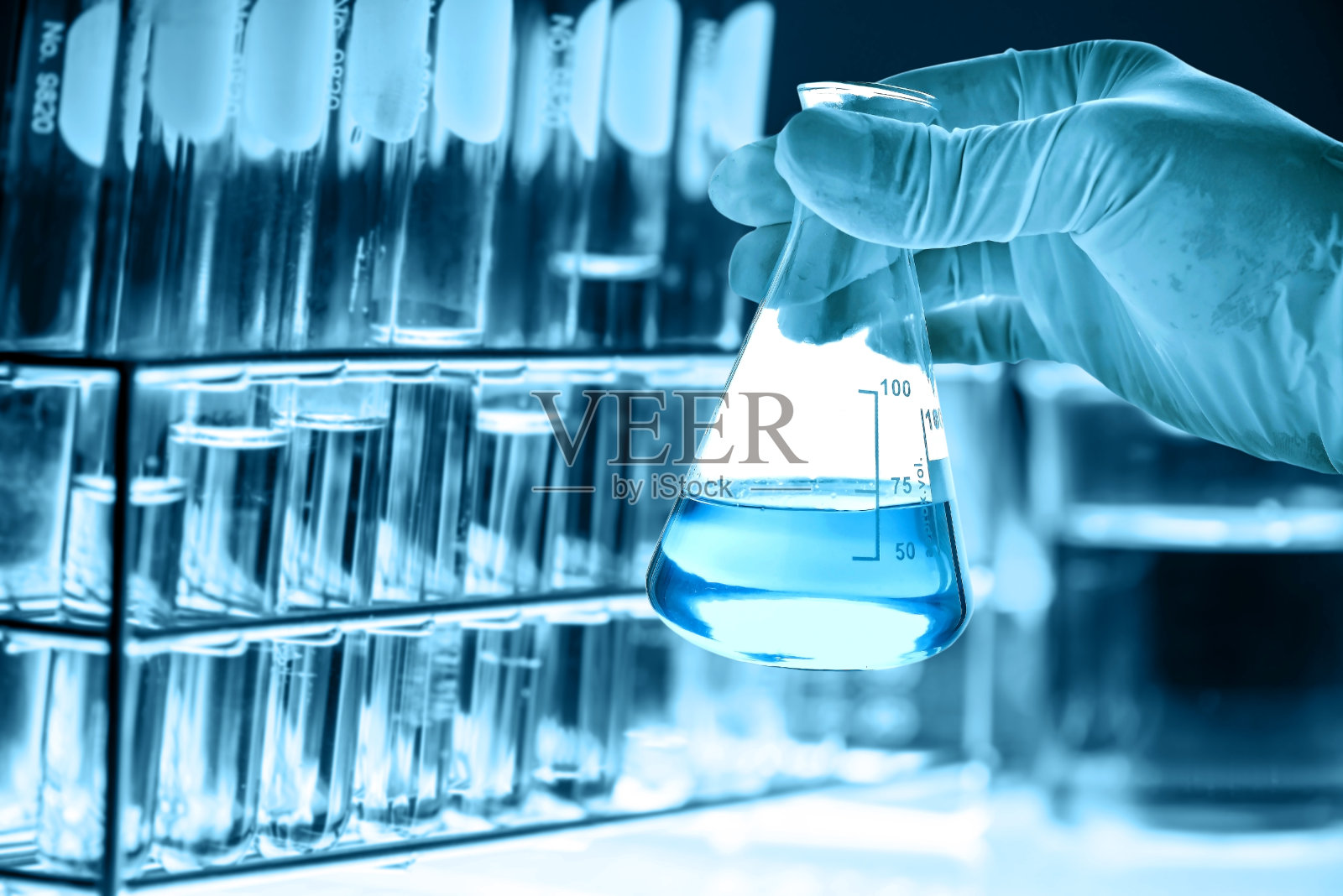 手握烧瓶与实验室玻璃器皿在化学实验室的背景，科学实验室研究和发展的概念照片摄影图片
