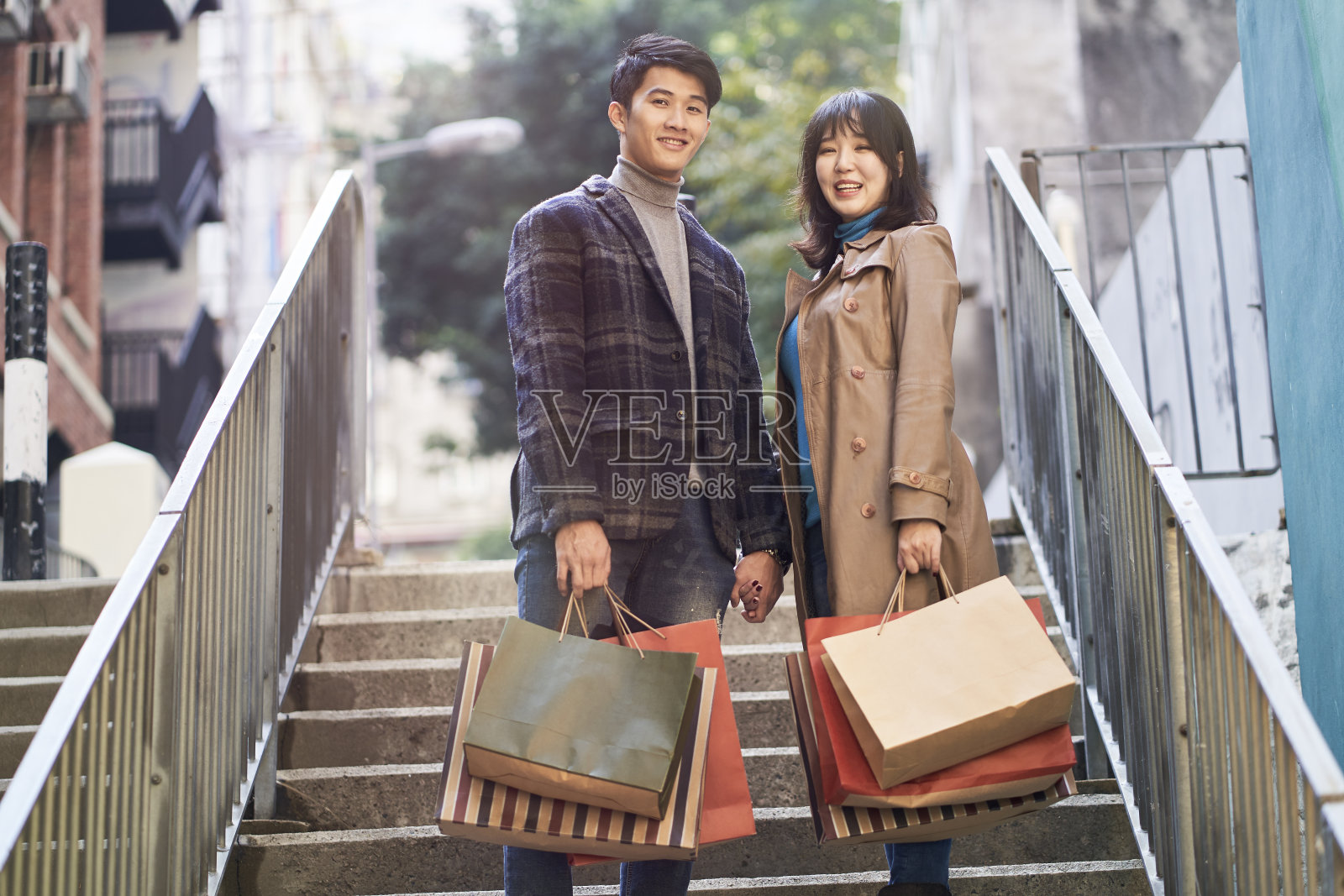 户外肖像的年轻亚洲夫妇与购物袋在手里照片摄影图片