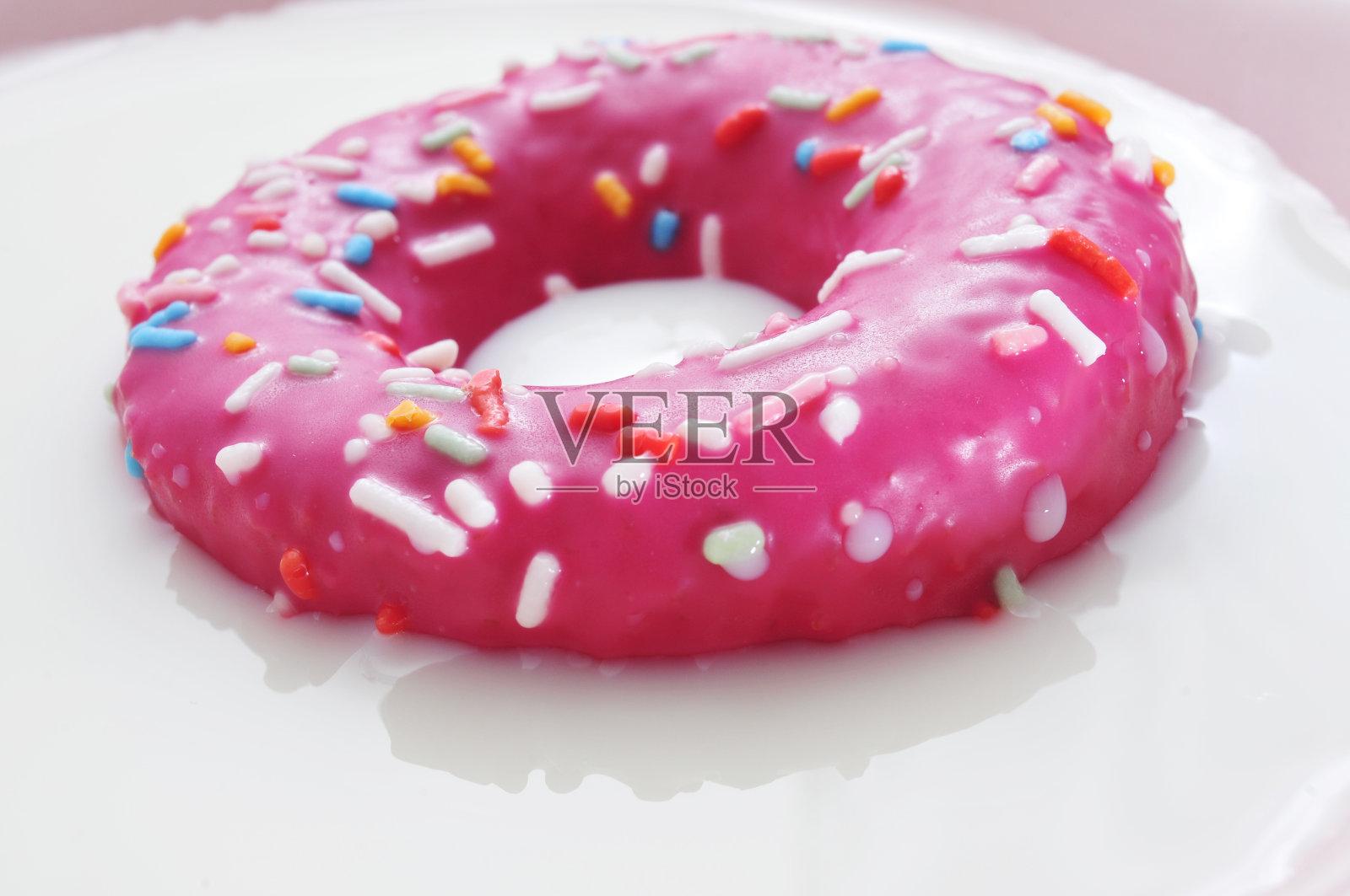 粉红色的甜甜圈泡在牛奶里照片摄影图片
