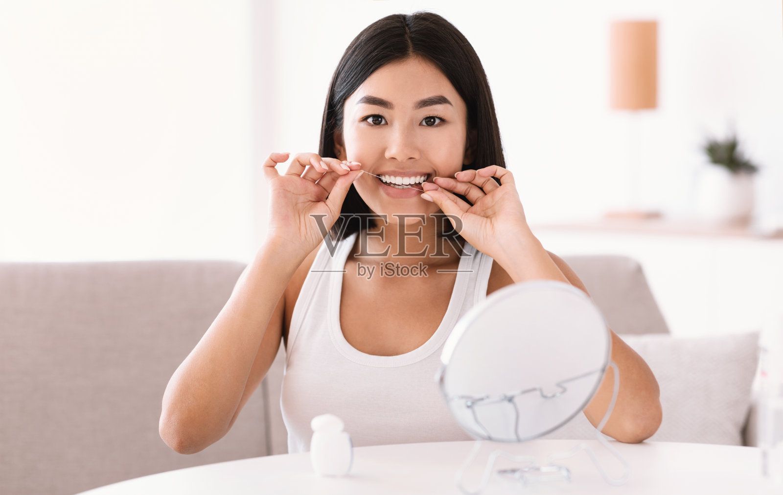 年轻的亚洲女士用牙线看着镜子照片摄影图片