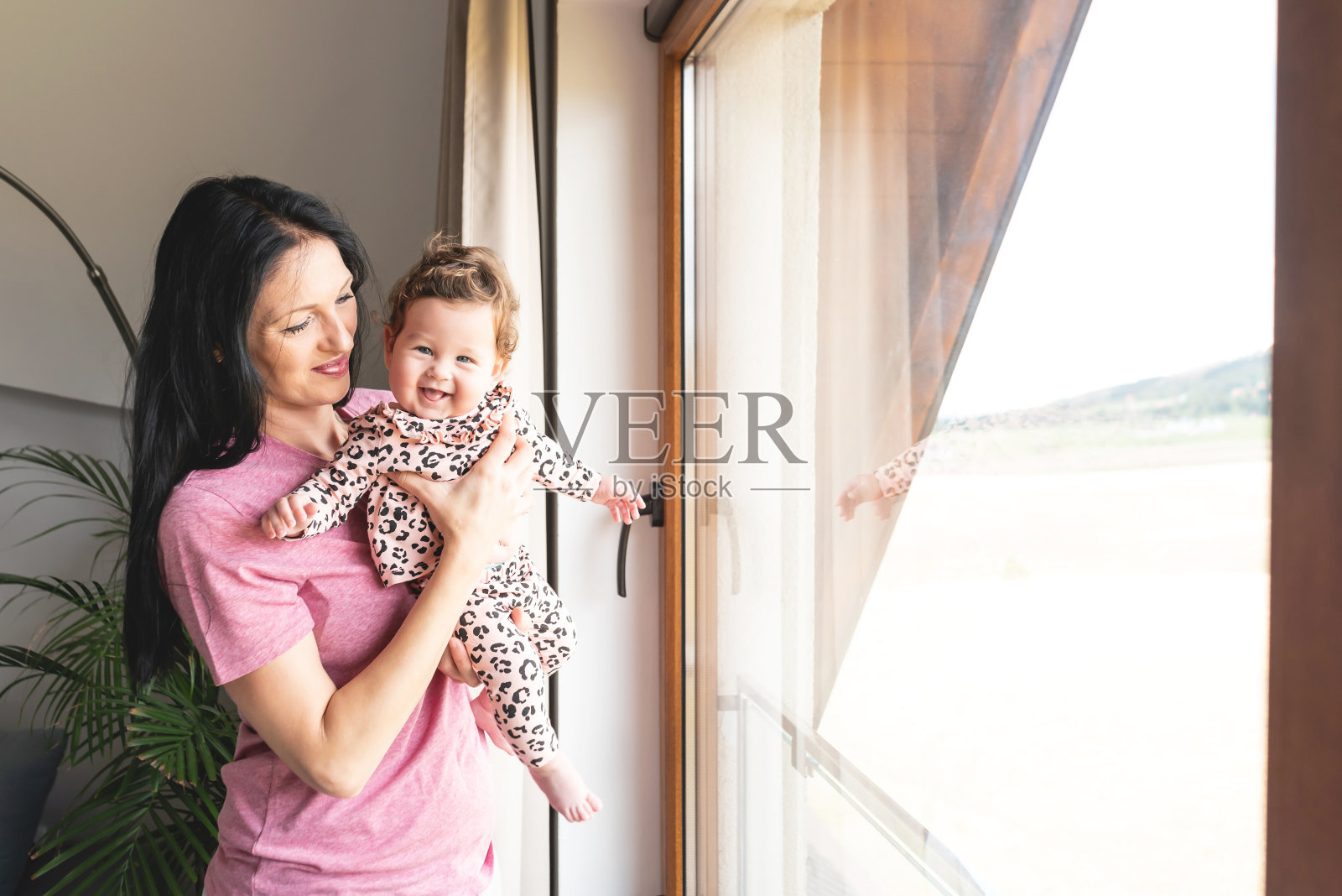 慈爱的母亲带着女儿靠近房子的窗户照片摄影图片