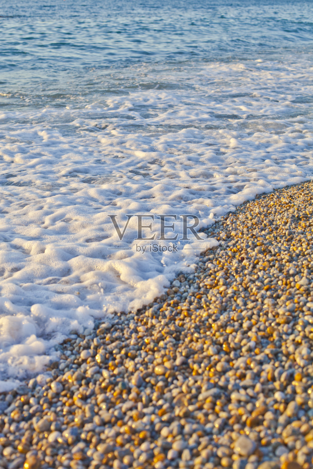 鹅卵石在海边游动。第勒尼安海的蓝色波浪。照片摄影图片