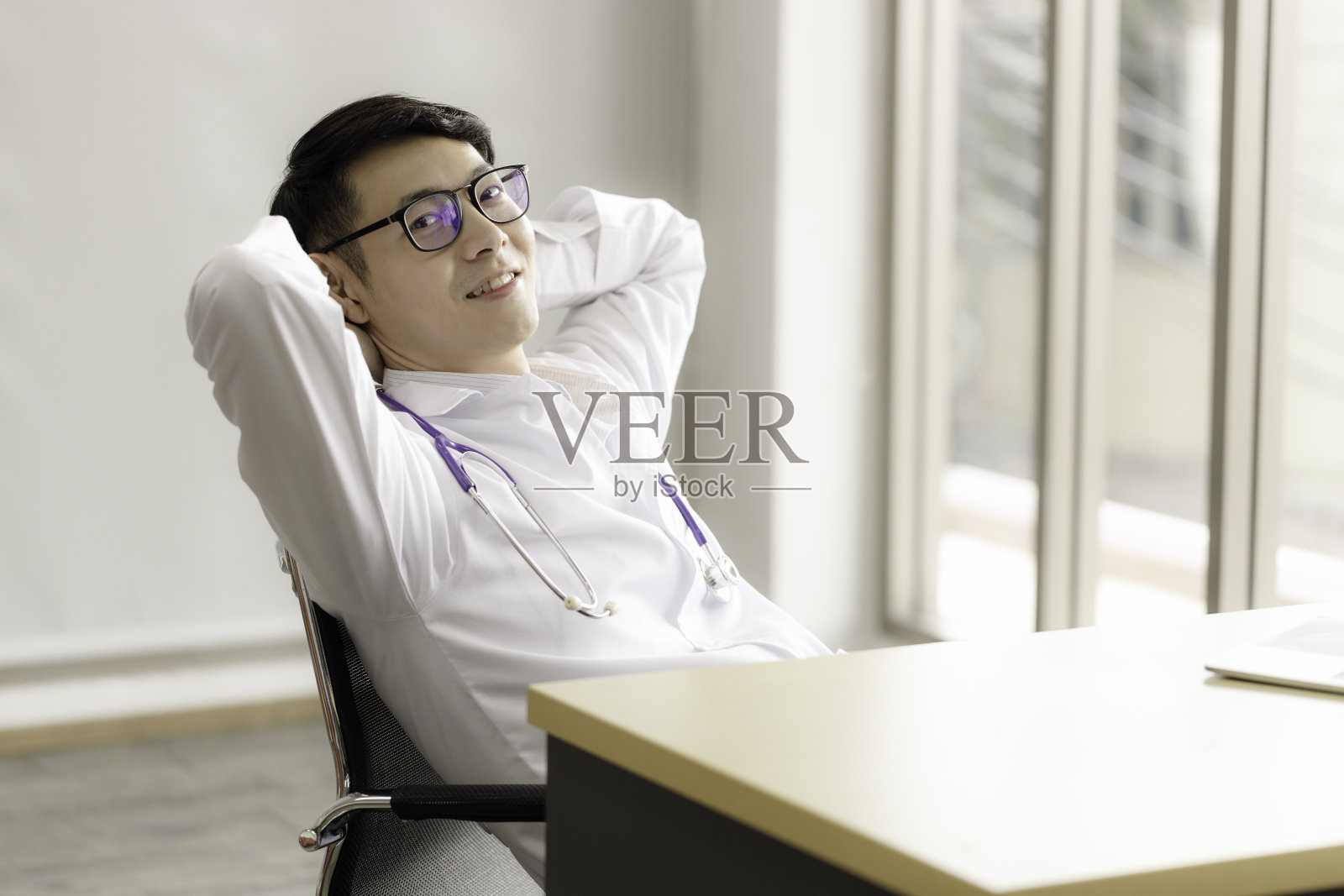 一位年轻的亚洲医生戴着眼镜在医院的房间里放松和微笑。医疗保健理念。照片摄影图片
