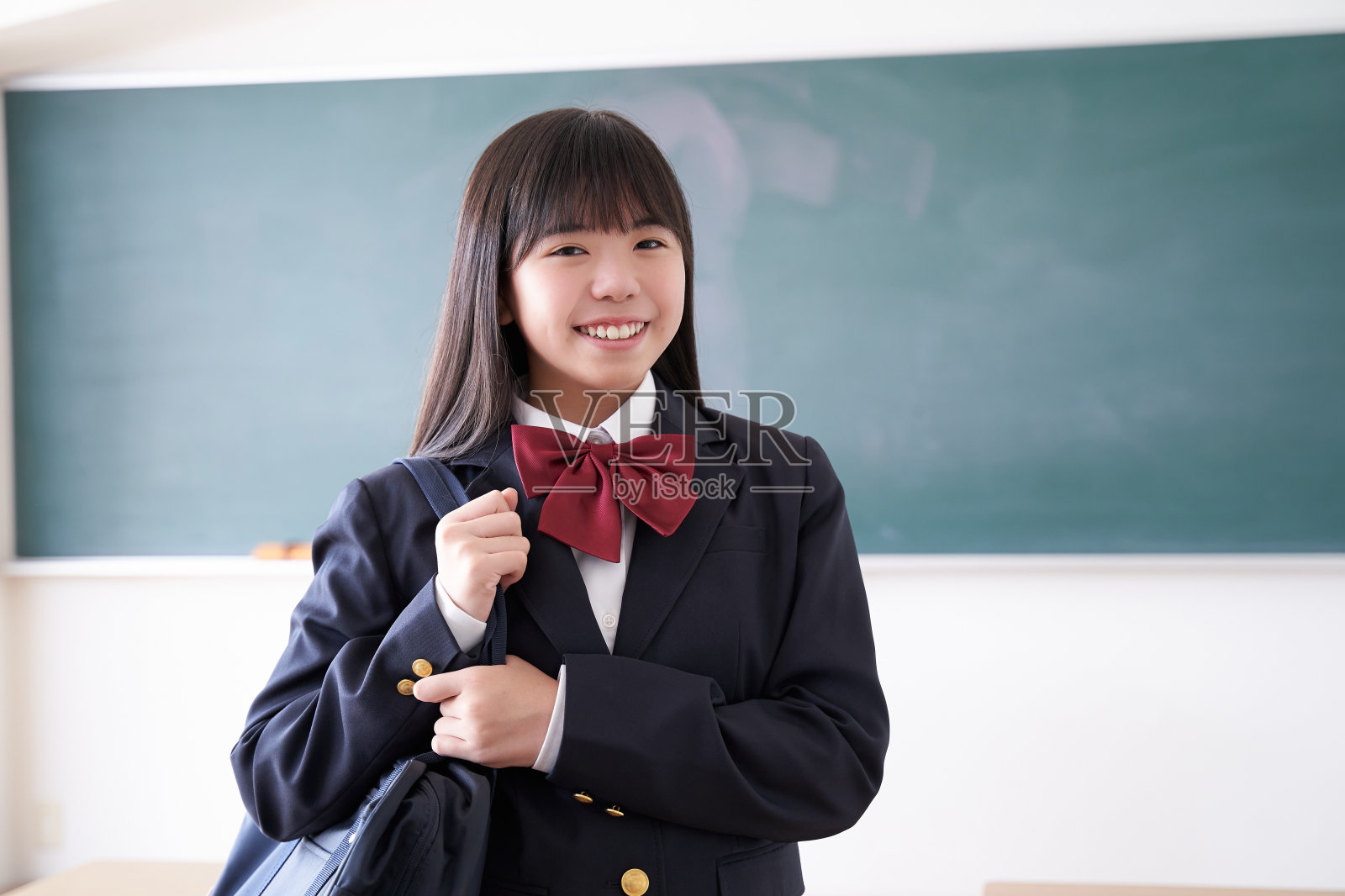 一个日本初中女孩拿着她的书包在教室里照片摄影图片