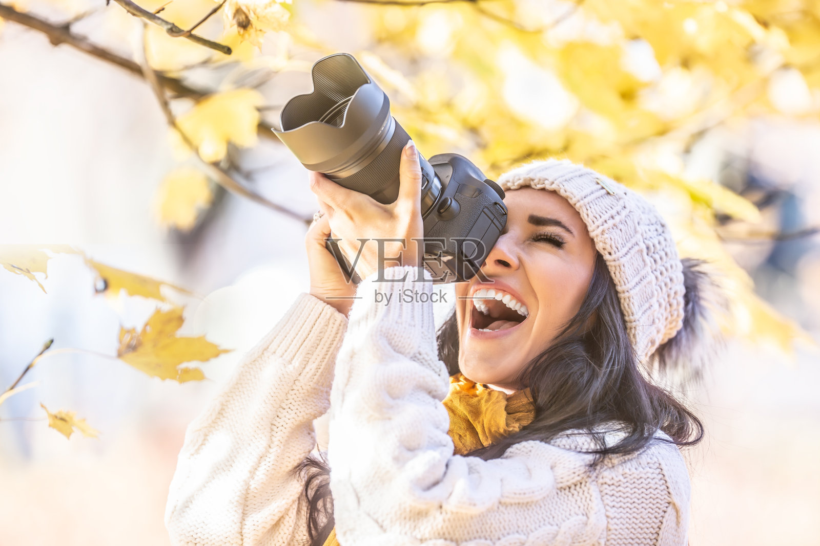 快乐的摄影师在一个冬天的帽子拍摄户外在多彩的秋天的自然。照片摄影图片