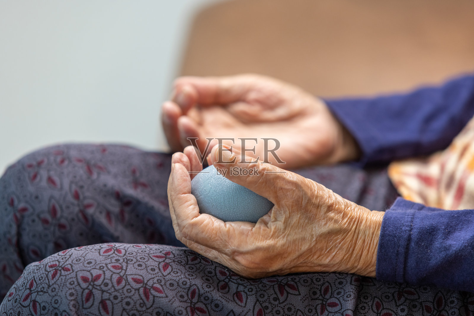 老年妇女做皮球锻炼手指、手掌、手脚肌肉，由护工照顾。照片摄影图片