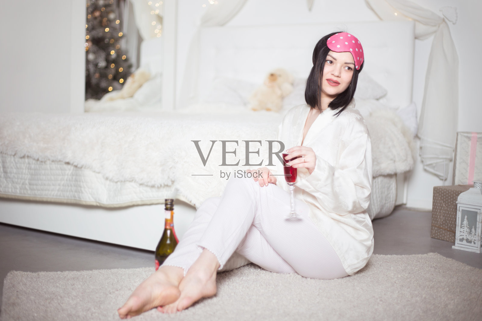 年轻漂亮的女人穿着睡衣，卧室里放着香槟。冬天的假期。照片摄影图片
