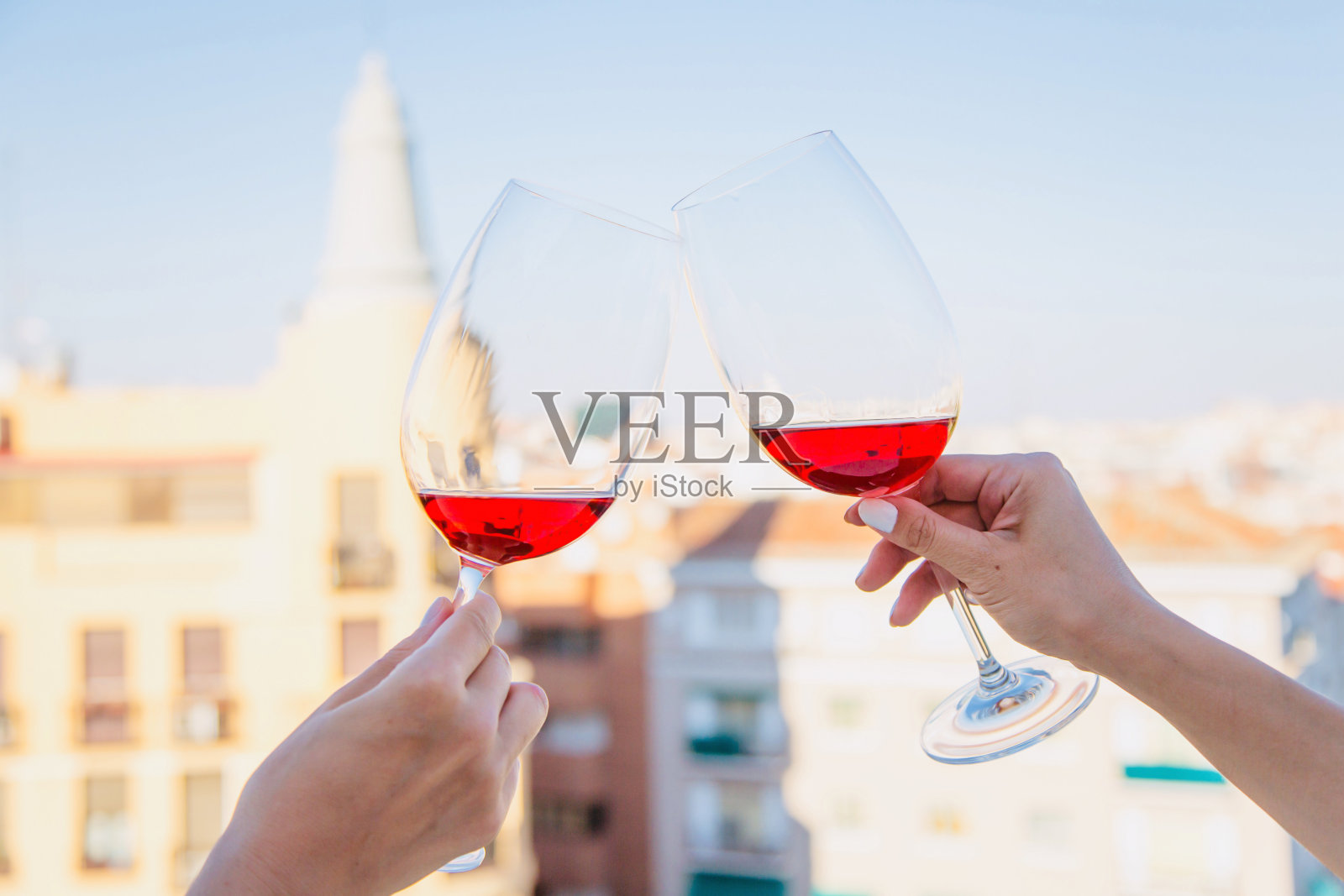 两杯红酒在女人的手对着天空。照片摄影图片