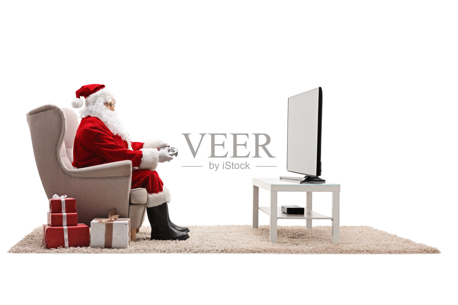 圣诞老人坐在扶手椅上，在电视上玩电子游戏照片摄影图片